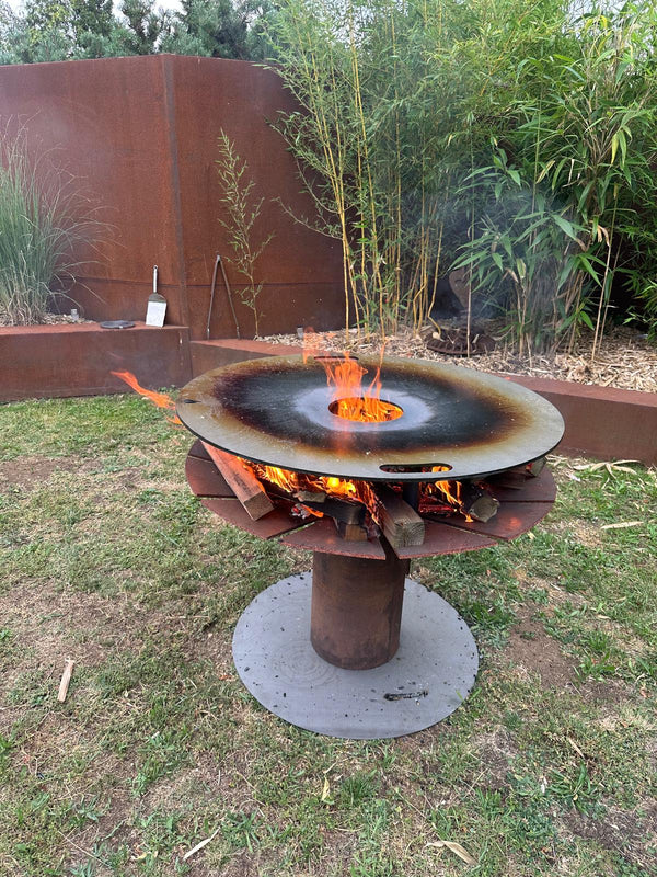 Feuerplatte auf Feuerschale mit Grilleinsatz und zentraler Hitzezone im Garten